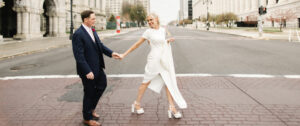 blonde bride holding grooms hand crossing a street in downtown albany, ny wedding by jp elario